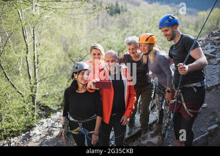 Group of seniors with instructor climbing rocks outdoors in nature ...