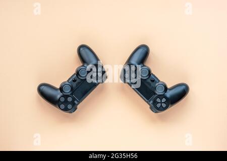 Two game controllers for a video game console or pc wireless black on light orange background, top view. Stock Photo