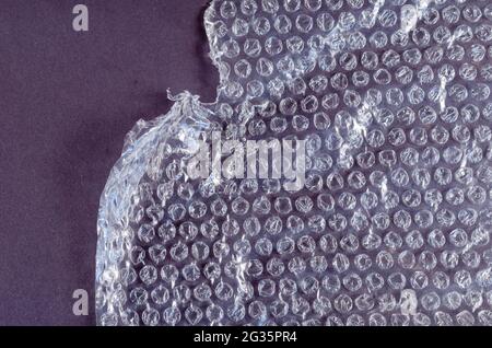Protective bubble wrap on colored background. Texture of plastic wrap with carelessly torn edge. Top view. Stock Photo