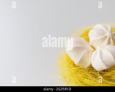 meringues in a yellow basket nest on a white background Stock Photo