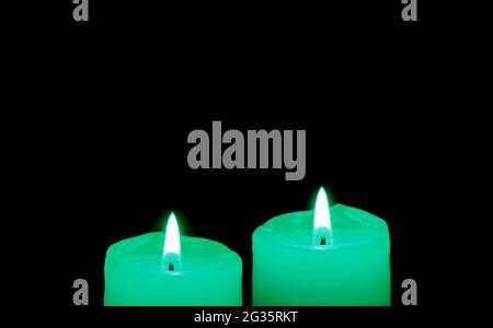 Glowing a pair of mint green candles in the dark with copy space Stock Photo