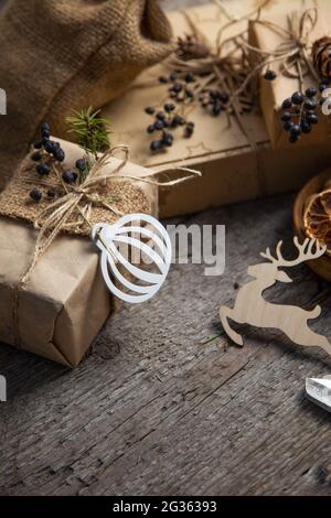 Gift wrapping for Christmas and New Year. Wooden background with place for text. Gift box in craft wrapping paper. Prepare for the holiday. Copy space Stock Photo