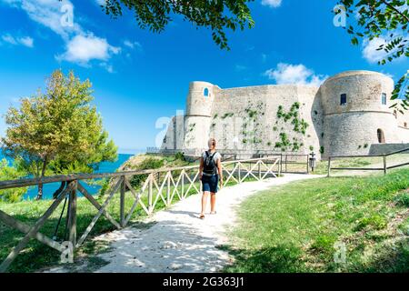 Rear view of woman walking towards the old complex of Castello Aragonese, Ortona, province of Chieti, Abruzzo, Italy Stock Photo