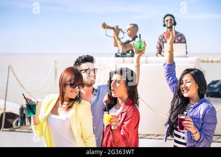 Funky people dancing music and having fun together at beach rave afterhour party - Deejay and trumpet player entertaining young happy friends Stock Photo