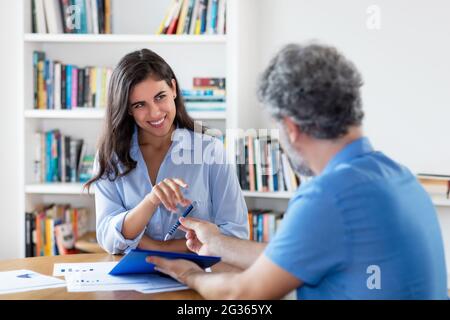 Young indian businesswoman signing contract after job interview at office of company Stock Photo