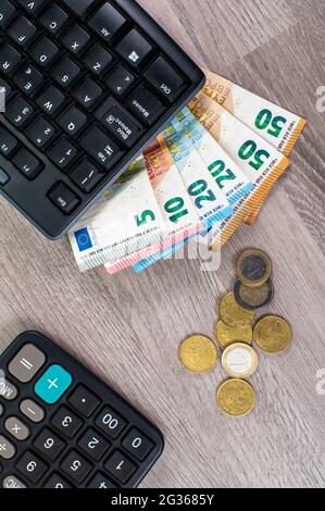 computer keyboard with euro money and calculator on wooden background Stock Photo