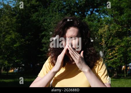 Girl sneezes because of the poplar fluff. Allergic reaction to poplar fluff Stock Photo