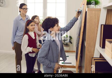 Smart intelligent kid boy answering at classroom board during school lesson Stock Photo