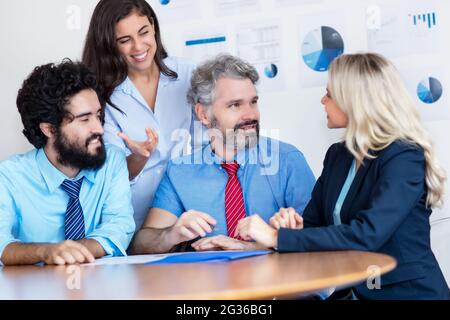 Mature adult businessman talking about strategy with international team at office of company Stock Photo