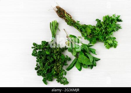 bundles of cilantro, mint and parsley isolated on white textured background. Stock Photo