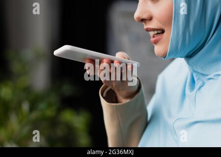 partial view of muslim businesswoman sending voice message on mobile phone Stock Photo