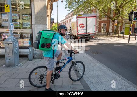 Uber eats take away  delivery man on a bicycle waiting at a pedestrian crossing in norwich city centre Stock Photo