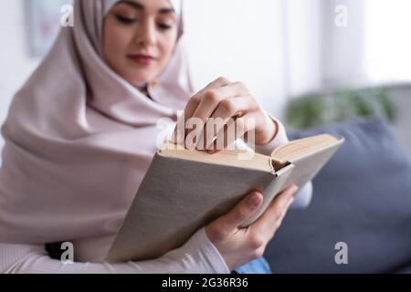 blurred muslim woman reading novel at home Stock Photo