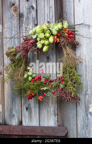 autumn wreath made from collected natural materials hanging at a barn door Stock Photo