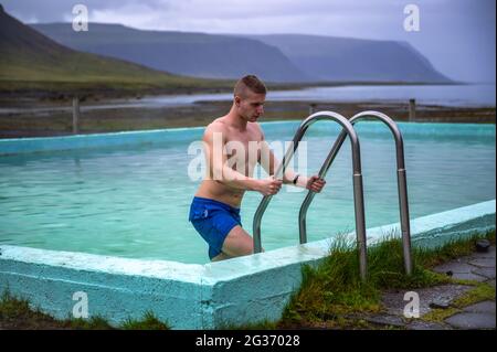 Boy gets out of the Reykjafjardarlaug Hot Pool in the Westfjords, Iceland Stock Photo