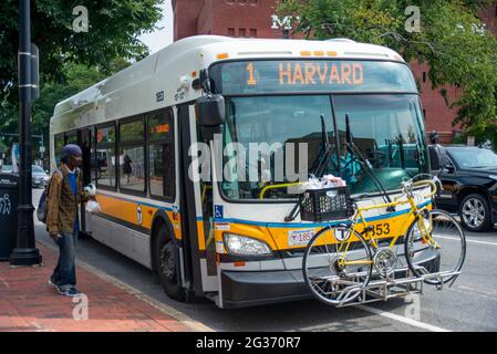 Local Harvard bus seen stopping near the University Campus, with members of the public having disembarked and seen walking in the distance Stock Photo