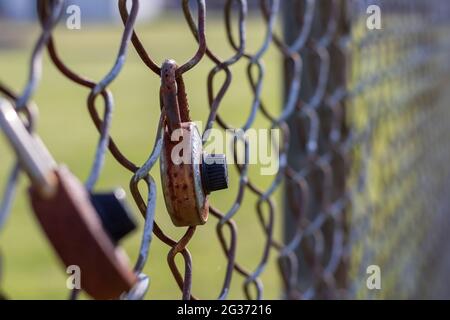 Selective focus of rusted combination lock on chain link fence. Sad nostalgia concept. Stock Photo
