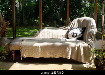 Analytical couch positioned against an open window overlooking a garden, used by psychotherapist treating patient with mental illness. Stock Photo