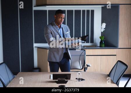 African american businessman reading documents while standing in meeting room at modern office Stock Photo