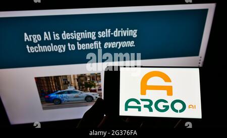 Person holding cellphone with logo of US driving technology company Argo AI LLC on screen in front of business webpage. Focus on phone display. Stock Photo