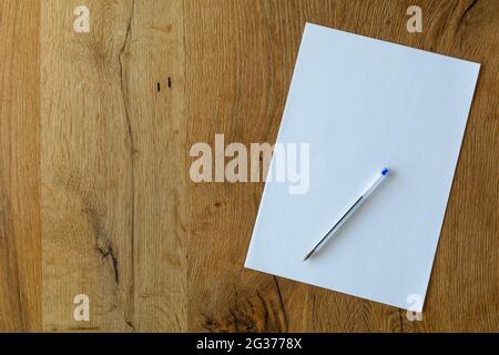 Blank sheet of paper and pen on a wooden desk. Stock Photo