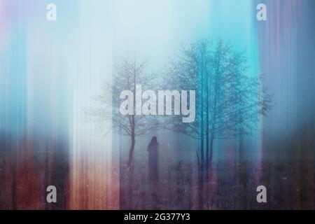 A double exposure of a spooky half transparent hooded figure. Over layered over an abstract, artistic, retro edit. On a moody foggy winters day in the Stock Photo