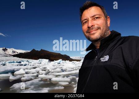 Man in front of icebergs, floating ice chunks, glacier ice, glacier, calving glacier, glacier lagoon, glacier lake, glacier lagoon Fjallsarlon Stock Photo