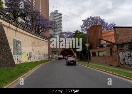 ROSARIO, ARGENTINA - Nov 08, 2020: General view of the entrance to the Arturo Illia tunnel with cars circulating surrounded by buildings and jacaranda Stock Photo