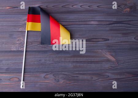 The flag of Germany with stick and copy space on grey wood. Stock Photo