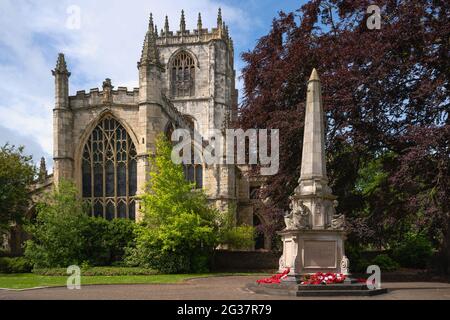 St Mary's church and War memorial under bright bluek sky as viewed from within public gardens on fine spring morning in Beverley, Yorkshire, UK. Stock Photo