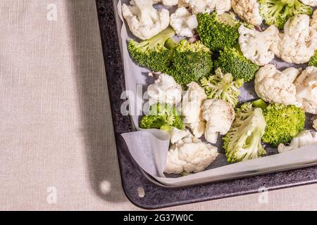 Assorted cauliflower and broccoli, ready to bake. The cooking food concept for a healthy lifestyle. A hard light, dark shadow, baking tray on a table, Stock Photo