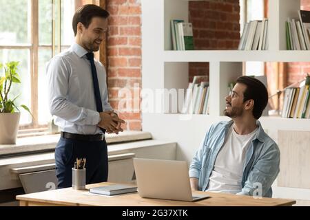 Happy friendly colleagues communicating in modern office room. Stock Photo