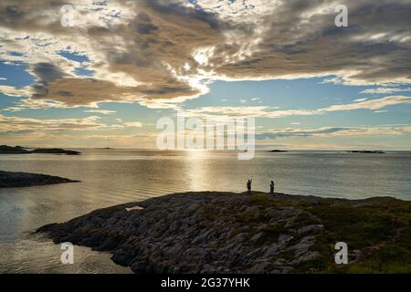 Young couple controlling the drone with remote control at the Norwegian coastline at sunset Stock Photo