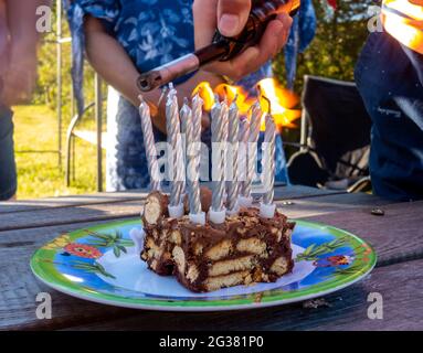 Lighting candles on a slice of birthday cake for the traditional 'sing Happy Birthday' and then blow out birthday candles. Stock Photo