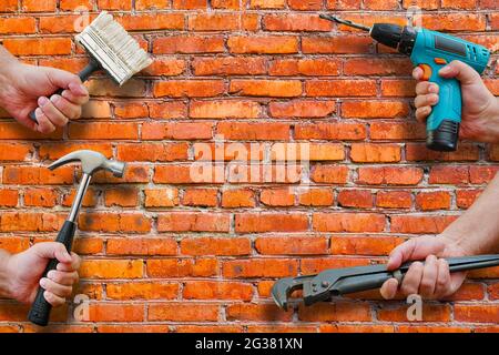 hands holding tools on brickwall background, copy space Stock Photo