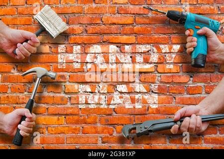 hands holding tools on brickwall background with handyman writing on it Stock Photo