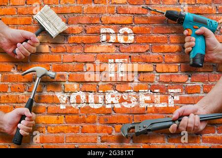 hands holding tools on brickwall background with do it yourself writing on it Stock Photo