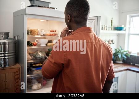 Young African man looking for something in his fridge Stock Photo