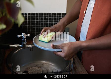 African man washing dishes in his kitchen sink at home Stock Photo