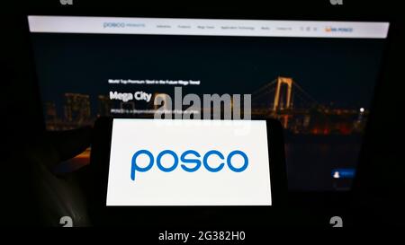 Person holding smartphone with logo of South Korean steel manufacturer POSCO on screen in front of company website. Focus on phone display. Stock Photo