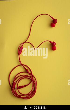 Red headphones with rolled wire, on a yellow background Stock Photo