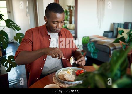 Young African man eating breakfast at his dining table Stock Photo