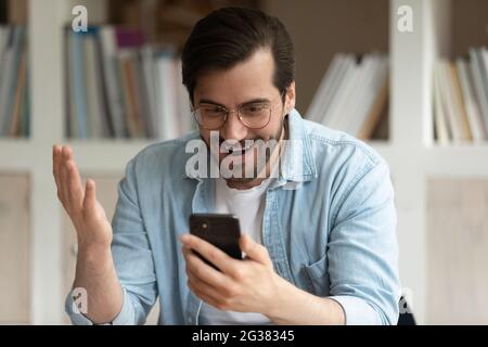 Surprised young man getting message with unbelievable news. Stock Photo