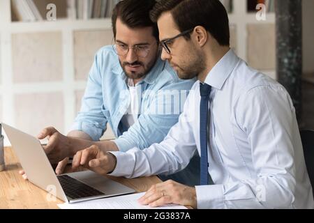 Skilled millennial employees working on computer in office. Stock Photo
