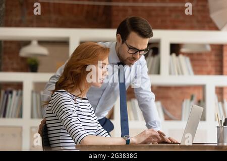 Confident male team leader helping new female employee. Stock Photo