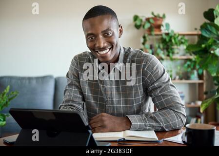 African businessman smiling while working on a tablet at home Stock Photo