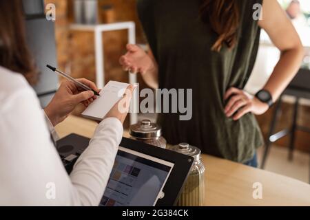 Midsection of caucasian female business owner taking order from caucasian female customer Stock Photo