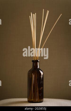 Dark glass diffuser bottle with natural reed sticks put on a pillow Stock Photo