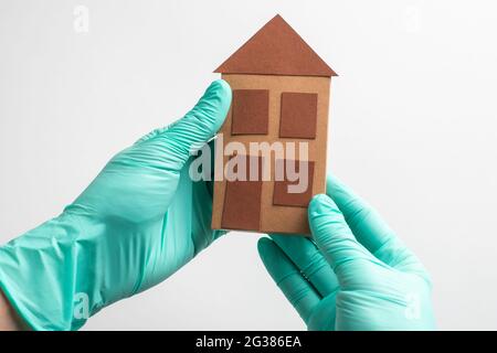 Hands in gloves holding a paper house on white background Stock Photo