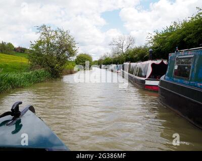 a line of moored narrowboats on the South Oxford canal seen from the bow of another boat Stock Photo
